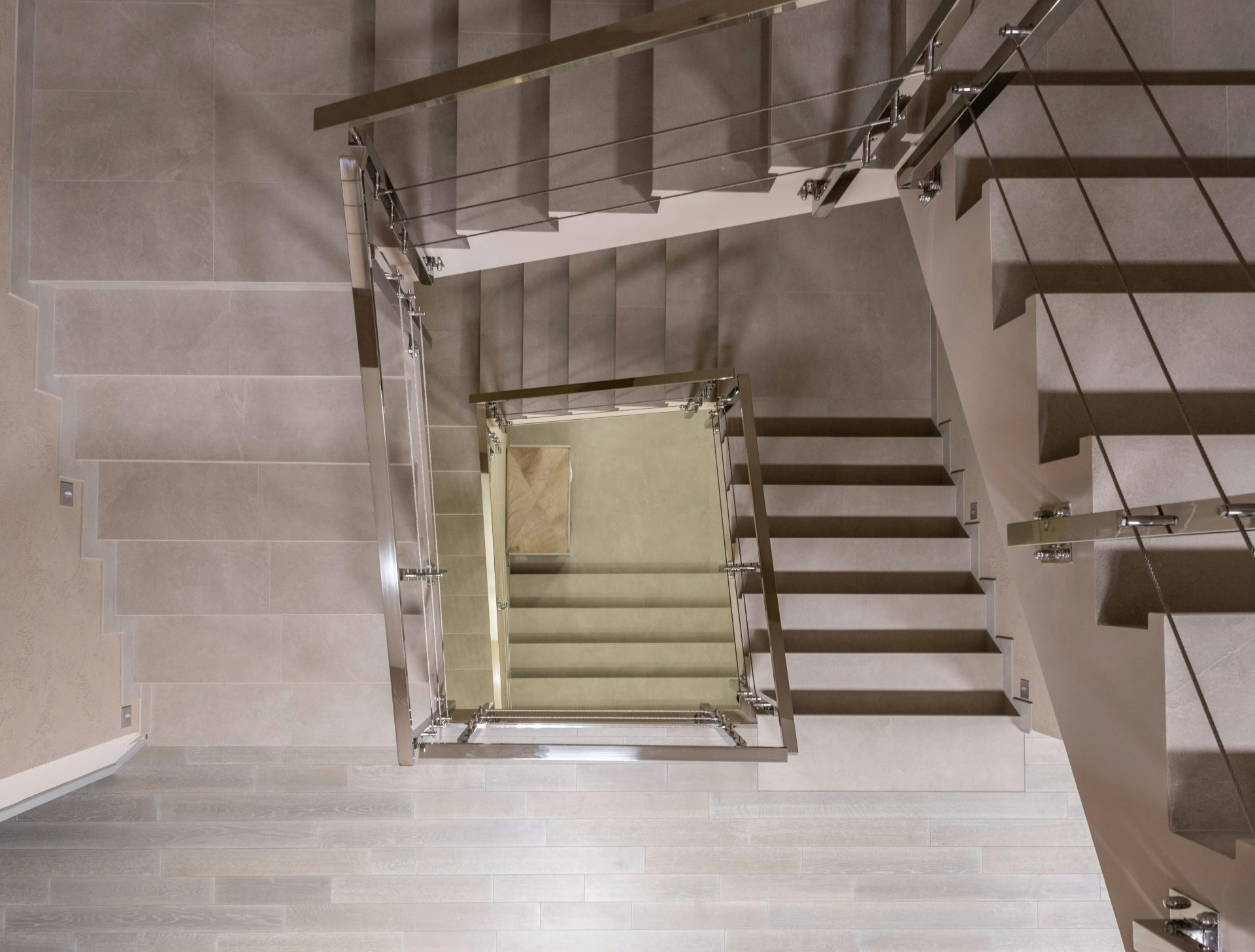 Draufsicht auf Treppen mit Metallgeländern und Absperrung in einem hellen, modernen und geräumigen mehrstöckigen Gebäude mit Laminatboden.